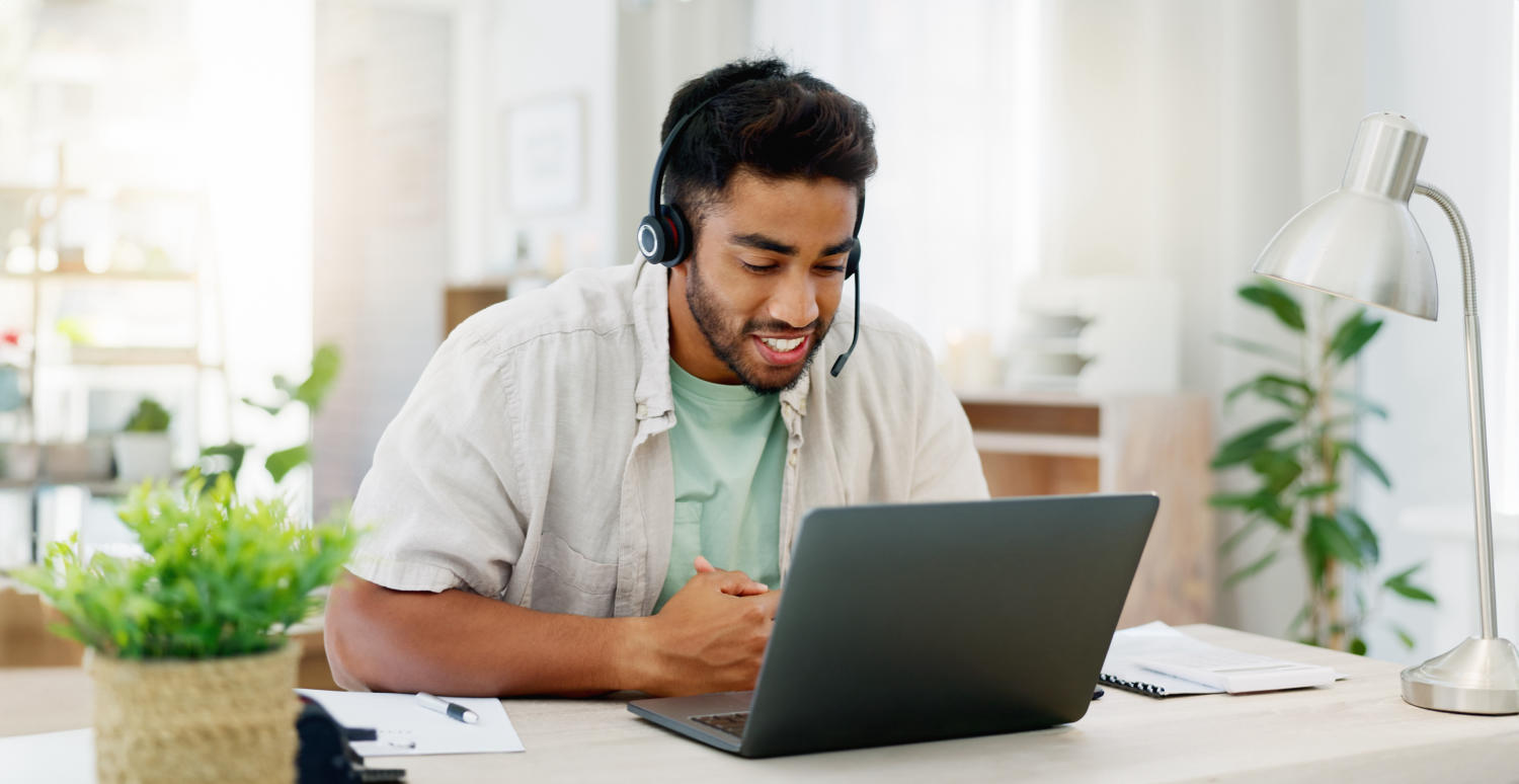 Mann mit Headset guckt auf Laptop