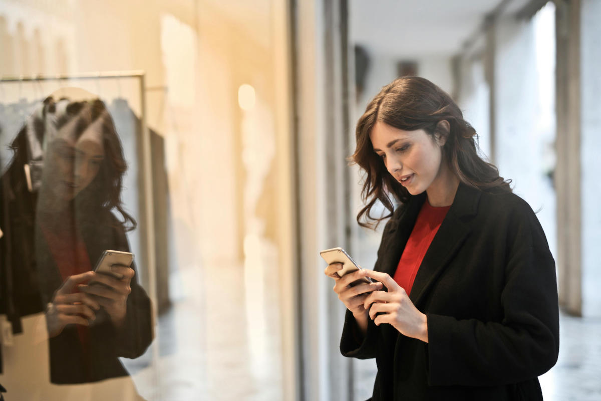 Frau guckt auf ihr Handy vor einem Geschäft