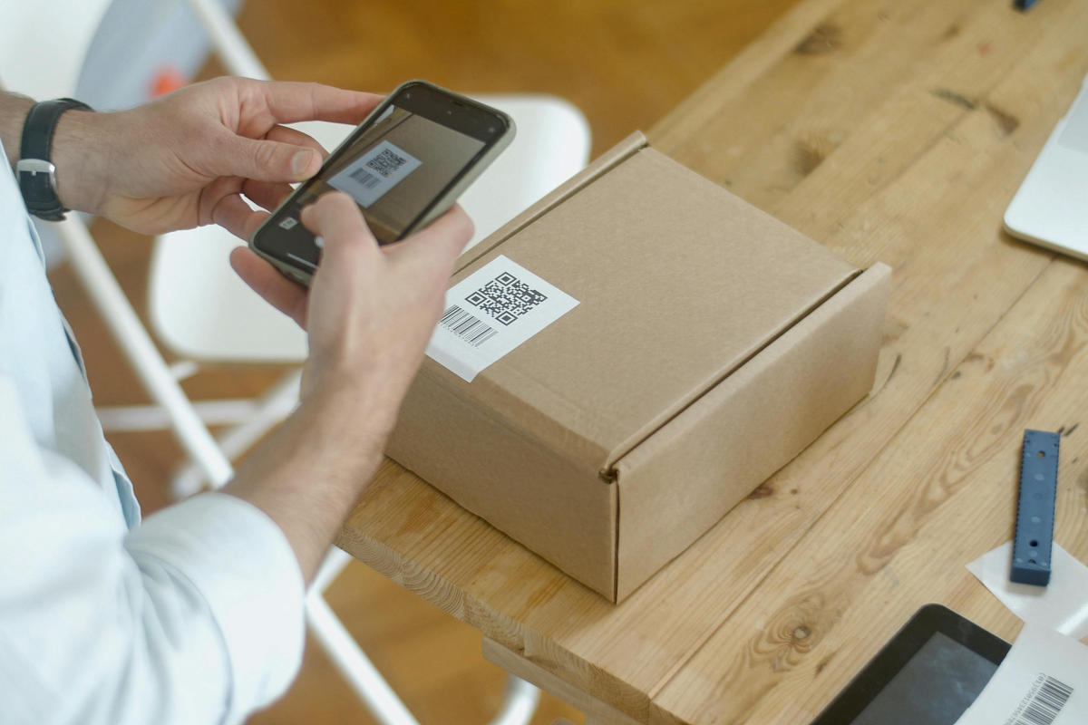 Frau scannt QR Code auf Paket mit Handy